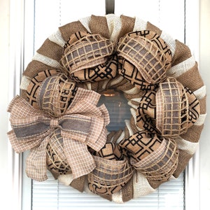 May include: A burlap wreath with a brown and white checkered bow and brown and black geometric patterned fabric accents.