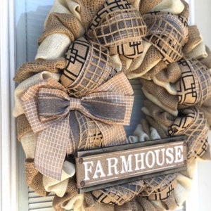 May include: A burlap wreath with a brown and white checkered bow and a wooden sign that says "FARMHOUSE".