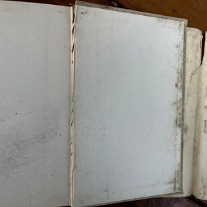 May include: Close-up of the spine of a book with a white cover and a decorative pattern along the edge. The book is closed and the pages are visible.