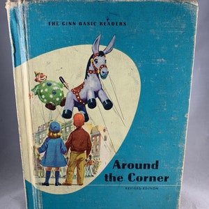 May include: A blue book with a white and red illustration of a clown holding a donkey balloon. The book title is "Around the Corner" with the text "The Ginn Basic Readers" and "Revised Edition" printed on the cover.