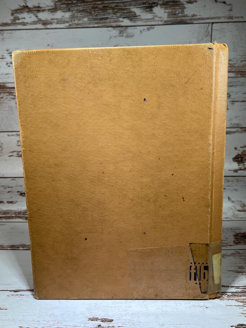 May include: A tan-colored hardcover book with a worn, textured cover. The book has a small, white label on the bottom right corner with the number "116" printed on it.