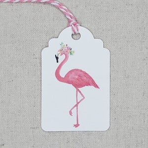 K&ouml;nnte beinhalten: Geschenk-Etikett mit einem rosa Flamingo, der eine Blumenkrone tr&auml;gt. Das Etikett ist wei&szlig; mit einem gewellten Rand und einem rosa-wei&szlig;en Band.