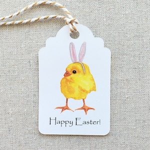 May include: A white gift tag with a yellow chick wearing pink bunny ears. The tag says "Happy Easter!"