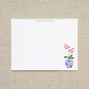 May include: A white card with the text "LILLIAN BLUE" printed in black at the top. A blue and white porcelain vase with pink flowers is illustrated in the bottom right corner.