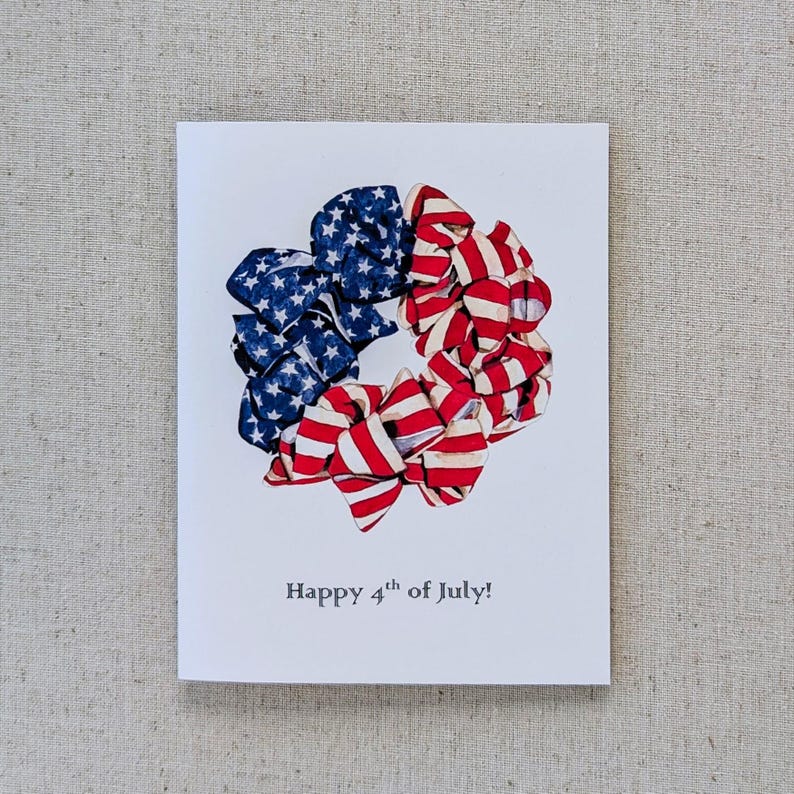 May include: A greeting card with a wreath made of red, white, and blue fabric bows. The wreath is in the shape of a circle and the bows are arranged in a circular pattern. The text "Happy 4th of July!" is printed below the wreath.
