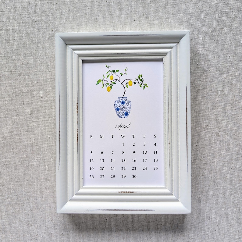May include: A white framed calendar for April. The calendar features a watercolor illustration of a lemon tree in a blue and white vase. The word "April" is written in cursive above the calendar dates.