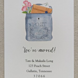 May include: A blue and white painted mailbox with a floral design and the word "POST" on the front. The mailbox is filled with envelopes and flowers. The text "We've moved!" is written below the mailbox, followed by the name "Tate & Makaila Long", the address "123 Peach Street", the city and state "Gallatin, Tennessee", and the zip code "37066".