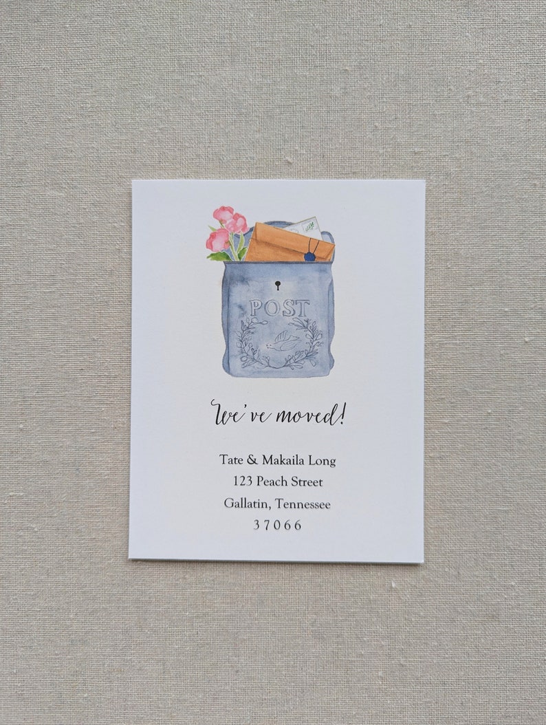 May include: A watercolor illustration of a blue mailbox with a brown envelope and pink flowers sticking out of the top. The mailbox has the word "POST" written on it. The text "We've moved!" is written below the mailbox, followed by the address "Tate & Makaila Long, 123 Peach Street, Gallatin, Tennessee 37066".