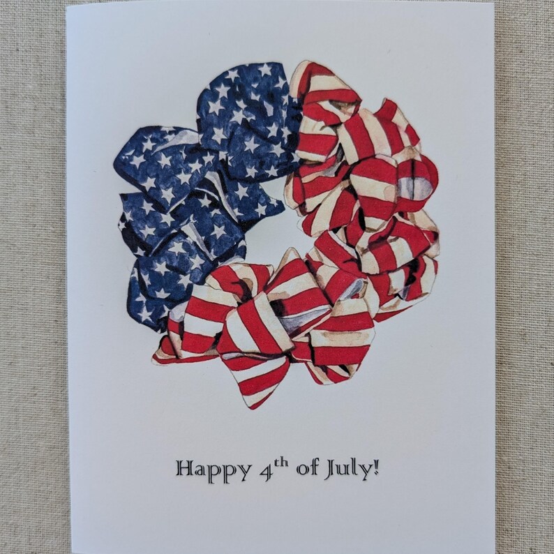 May include: A greeting card with a wreath of red, white, and blue fabric bows. The card says "Happy 4th of July!"