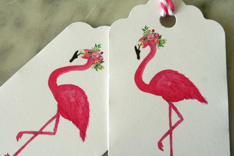 K&ouml;nnte beinhalten: Zwei rosa Flamingo-Geschenk-Etiketten mit Blumenkr&auml;nzen. Die Etiketten sind wei&szlig; mit gewellten R&auml;ndern und einem Loch f&uuml;r eine Schnur.