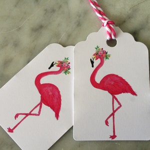 K&ouml;nnte beinhalten: Zwei rosa Flamingo-Geschenk-Etiketten mit Blumenkr&auml;nzen. Der Flamingo links schaut nach links und der Flamingo rechts schaut nach rechts. Beide Etiketten haben gewellte R&auml;nder.