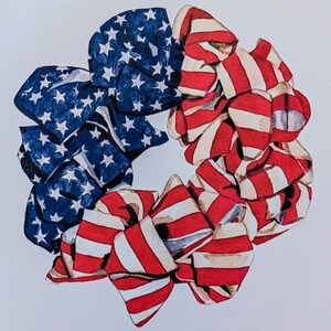 May include: A red, white, and blue fabric hair scrunchie in the shape of a bow. The scrunchie is made of two pieces of fabric, one with red and white stripes and the other with blue and white stars.