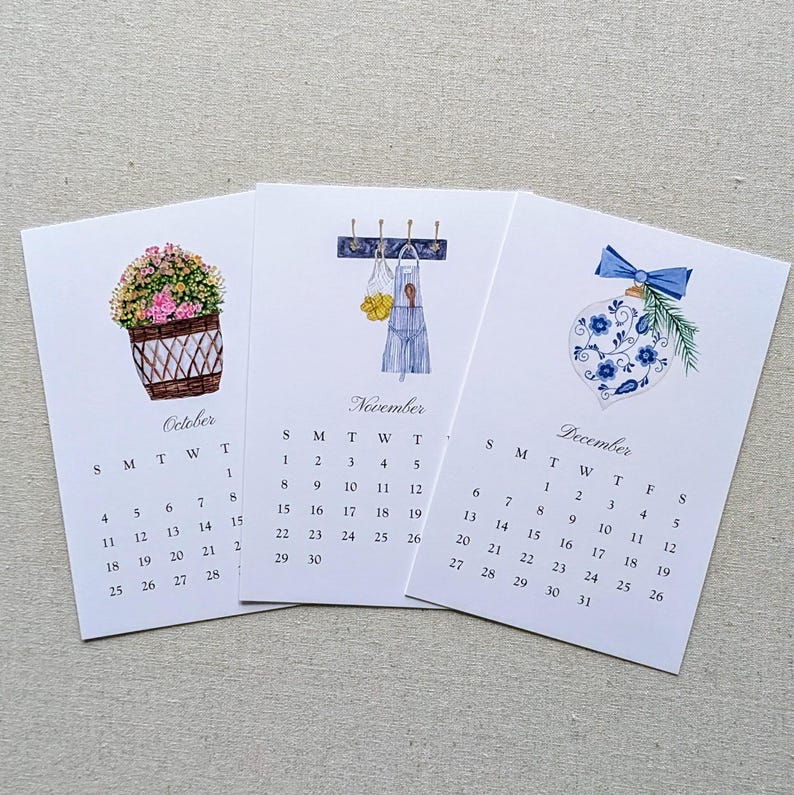 May include: Three watercolor calendars for October, November, and December. Each calendar features a different illustration: a flower basket, a kitchen scene, and a Christmas ornament. The calendars display the days of the month.