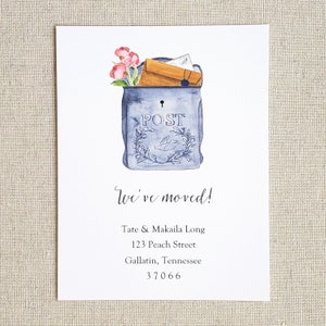 May include: A blue and white mailbox with a floral arrangement and the word "POST" on the front. The text "We've moved!" is written below the mailbox, followed by a new address: Tate & Makaila Long, 123 Peach Street, Gallatin, Tennessee 37066.