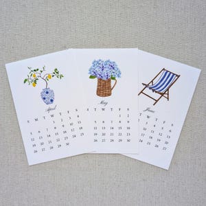 May include: Three-month calendar cards for April, May, and June. Each card features a watercolor illustration: a lemon tree in a vase, blue hydrangeas in a basket, and a blue-striped beach chair. The calendar dates are visible.
