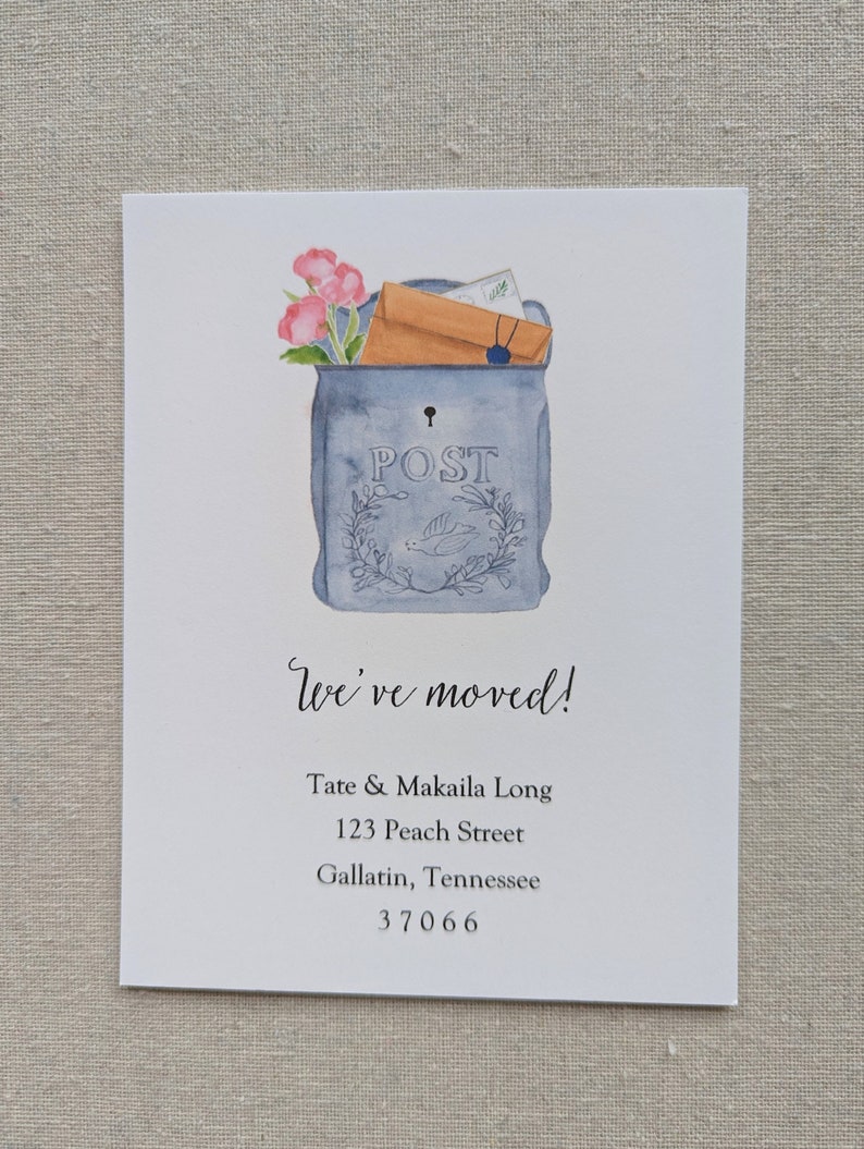 May include: A watercolor illustration of a blue mailbox with a brown envelope and pink flowers sticking out of the top. The mailbox has the word "POST" written on it. The text "We've moved!" is written below the mailbox, followed by the address "Tate & Makaila Long, 123 Peach Street, Gallatin, Tennessee 37066".