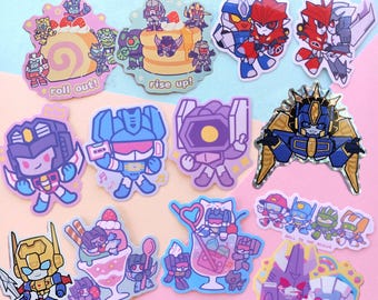Könnte beinhalten: Eine Sammlung von 11 bunten Cartoon-Aufklebern mit Transformers-Charakteren. Die Aufkleber zeigen verschiedene Szenen, darunter die Charaktere, die Kuchen essen, Eis essen und in einem Raumschiff fahren. Der Text auf den Aufklebern lautet "roll out!" und "rise up!"