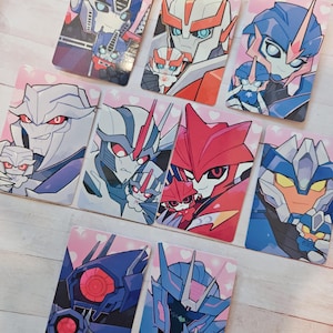 Puede incluir: Una colección de nueve tarjetas rectangulares con ilustraciones estilizadas de varios personajes robóticos, cada uno sosteniendo una versión más pequeña de sí mismo sobre un fondo rosa claro decorado con pequeños corazones blancos.