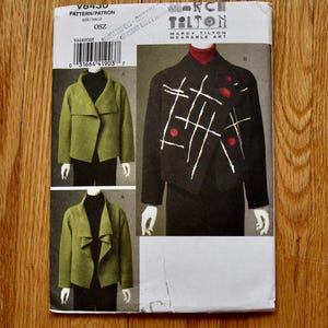 May include: A Marcy Tilton sewing pattern envelope V8430 for a jacket. The front shows two versions: a solid olive green jacket with a wide collar and a black jacket featuring white stitched lines and red circular accents. Text includes V8430 and OSZ.