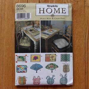 May include: A Simplicity Home pattern for place mats and chair pads. The pattern features various designs, including floral, fan, and geometric patterns. The package includes a photo of a dining table setting with place mats and chair pads.