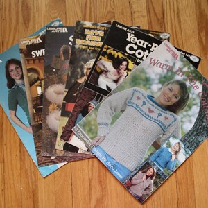 Peut inclure: Un ensemble de cinq livrets de loisirs créatifs Leisure Arts présentant divers modèles de tricot et de crochet. Les couvertures affichent des photographies de personnes portant des pulls, des bonnets et des écharpes, avec des titres comme Warm in the Country.