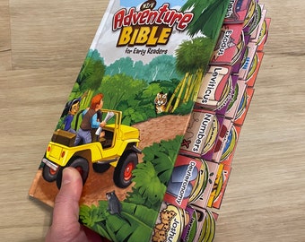 May include: A colorful children's book titled "NIV Adventure Bible for Early Readers" with tabs for each book of the Bible, including Genesis, Exodus, Leviticus, Numbers, Deuteronomy, and Joshua.