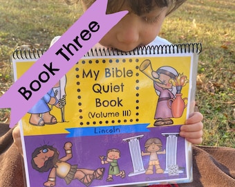 May include: A child is reading a yellow and purple book titled "My Bible Quiet Book (Volume III) Lincoln". The book has illustrations of people and objects from the Bible.