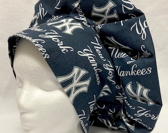 May include: A dark blue scrub hat with a white print of the New York Yankees logo and the words "New York Yankees".