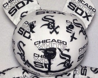 May include: White plush teddy bear with black and white Chicago White Sox logos printed all over. The bear has black button eyes and a black nose.