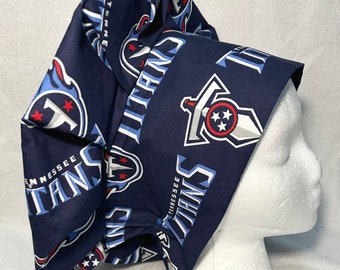 May include: A blue and white patterned surgical scrub hat with the Tennessee Titans logo repeated throughout. The hat is made of a soft, comfortable fabric and is designed to be worn by medical professionals.