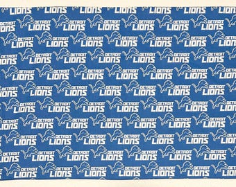 May include: Blue fabric with a repeating pattern of the Detroit Lions logo and text. The logo features a lion, and the text reads "DETROIT LIONS". The fabric is a solid blue color.