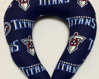 May include: A blue and white travel neck pillow with the Tennessee Titans logo repeated on the fabric. The logo features a sword and a star.