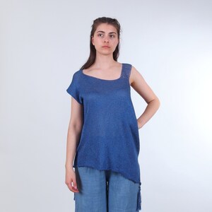May include: A blue knit top with a crochet detail on the shoulder strap. The top has a slightly asymmetrical hemline and is made of a lightweight fabric.