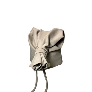 May include: A beige knit hat with a bow on top and two long ties. The hat has a small label with the word "SRE" on it.