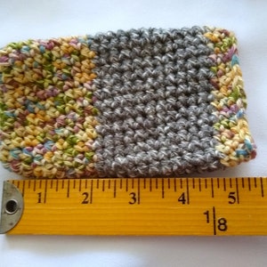 May include: A crocheted gray and multi-colored coaster with a textured surface. The coaster measures approximately 4 inches wide.