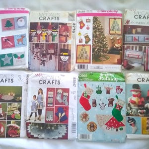 May include: A collection of craft pattern envelopes featuring holiday-themed designs. The patterns include Christmas ornaments, snowmen, stockings, and other festive decorations. The envelopes display various colors and illustrations.