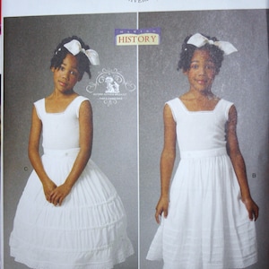May include: A vintage sewing pattern for a white dress and bloomers for a girl. The pattern is from Butterick and is number B5901. The pattern is for sizes 1-14.