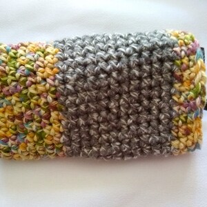 May include: A crocheted eyeglass case with a colorful patchwork design on one side and a gray crocheted design on the other side.