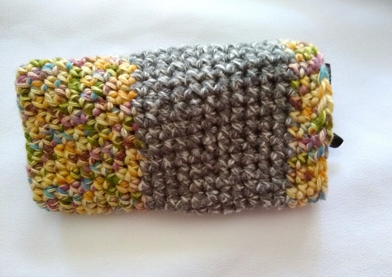 May include: A crocheted eyeglass case with a colorful patchwork design on one side and a gray crocheted design on the other side.