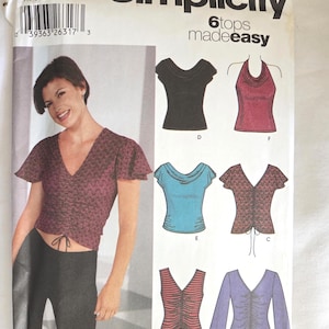 May include: Simplicity sewing pattern for six tops. The pattern features a woman wearing a burgundy top with a V-neck and drawstring. The pattern includes illustrations of various top styles, including a black scoop neck and a red halter top.