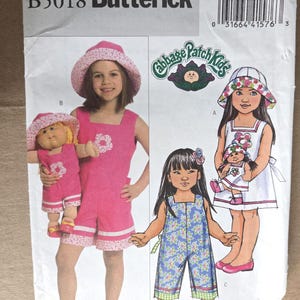 May include: A vintage Butterick sewing pattern, B5018, featuring illustrations of children's clothing. The pattern includes designs for rompers and dresses, with a Cabbage Patch Kids theme. The cover shows a pink romper and a blue floral romper.
