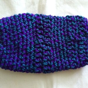 May include: A purple and teal knitted headband with a textured pattern.