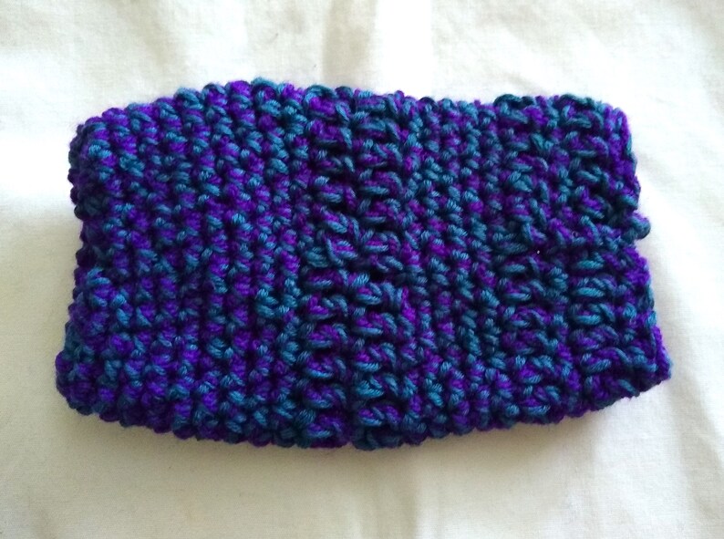 May include: A purple and teal knitted headband with a textured pattern.