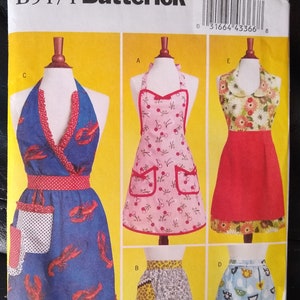 May include: A sewing pattern for five different apron designs. The aprons feature various prints, including cherries, lobsters, and birds. The pattern is for sizes small, medium, and large.