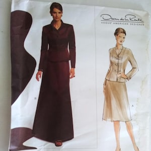 May include: A sewing pattern for a two-piece suit by Oscar de la Renta, Vogue American Designer. The pattern shows a long skirt and a jacket with a button-up front. The skirt is brown and the jacket is beige.