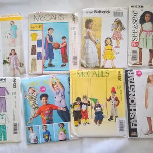 May include: A collection of children's sewing patterns from various brands, including McCall's, Butterick, and Simplicity. The patterns feature illustrations of children's clothing designs, such as dresses, tops, and pants. The patterns are in various sizes.