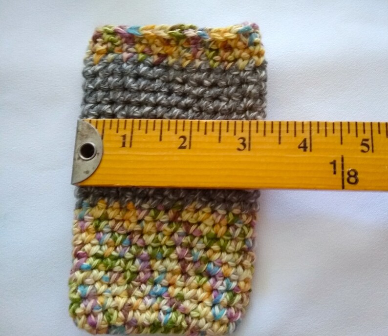 May include: A crocheted gray and multi-colored pouch with a yellow ruler measuring 4 1/8 inches.