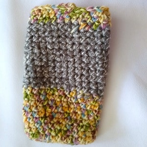 May include: A gray crocheted phone case with a colorful crocheted border. The border is made of a multi-colored yarn with shades of yellow, green, pink, and blue.