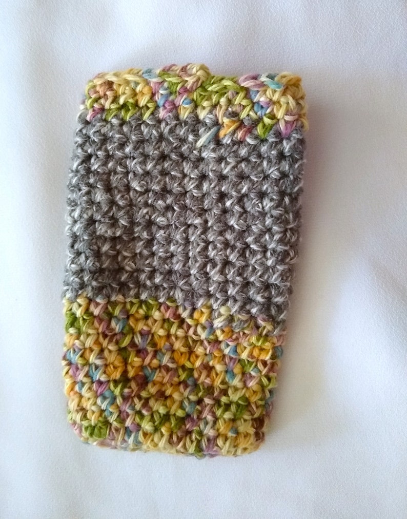 May include: A gray crocheted phone case with a colorful crocheted border. The border is made of a multi-colored yarn with shades of yellow, green, pink, and blue.