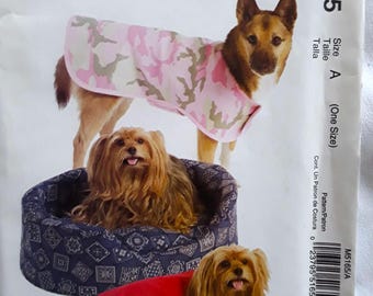 May include: An image of a dog wearing a pink camouflage coat, with two other dogs in the foreground. The image also shows a dog bed and a red dog coat. The text "Easy stitch'n save" and "M5165 by McCall's" are visible.
